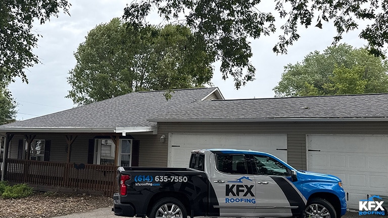 Final inspection photo of a recently replaced asphalt shingle roof with KF-X roofing company truck in the driveway