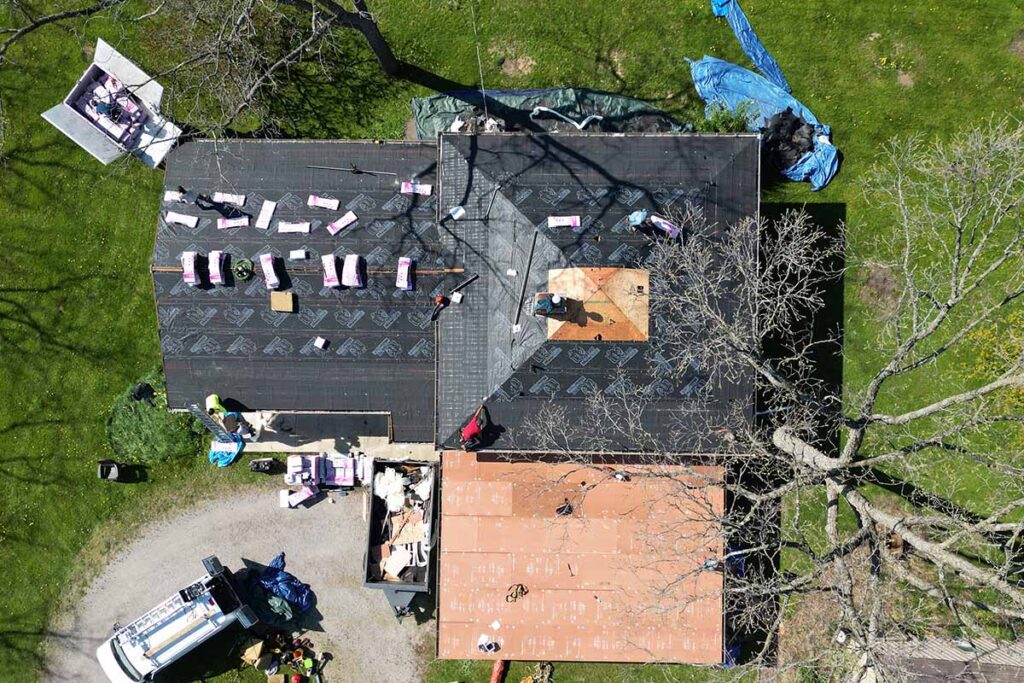 Aerial photos showing the crew preparing the asphalt surface for the installation of asphalt shingles and EPDM roofing.