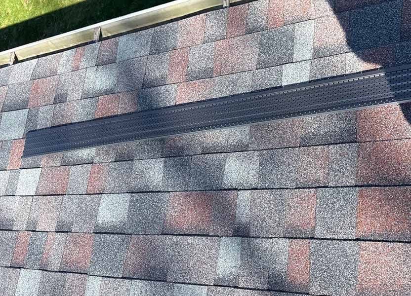 Image of a completed asphalt shingle roof replacement on the rooftop, ready for new gutter guard installation.