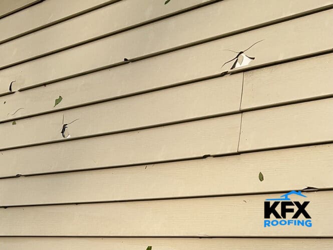 Hail damage to vinyl siding showing impact punctures and cracks on residential home